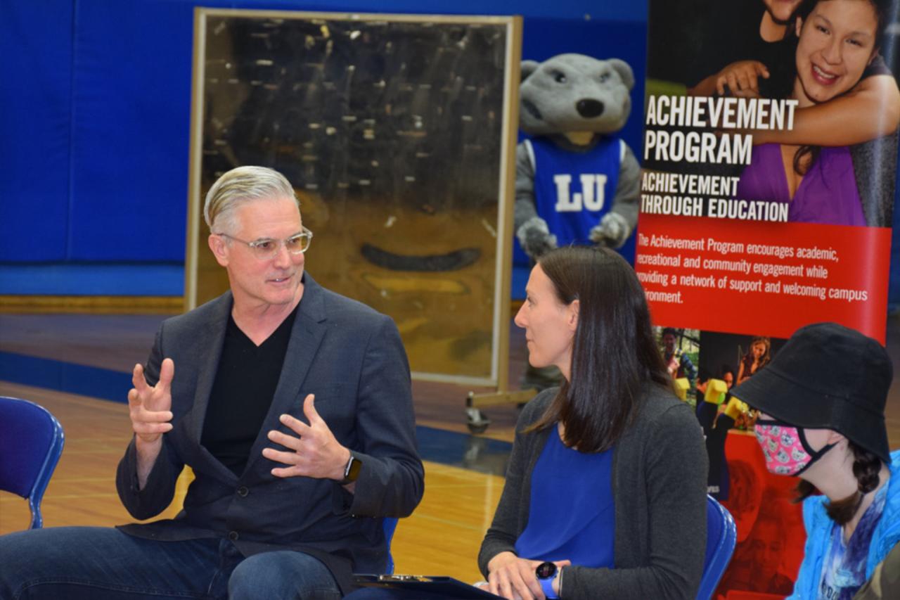 Tom Warden and Amanda Stefanile spoke to students about the Achievement Program while a special guest, Wolfie, snuck up behind them.