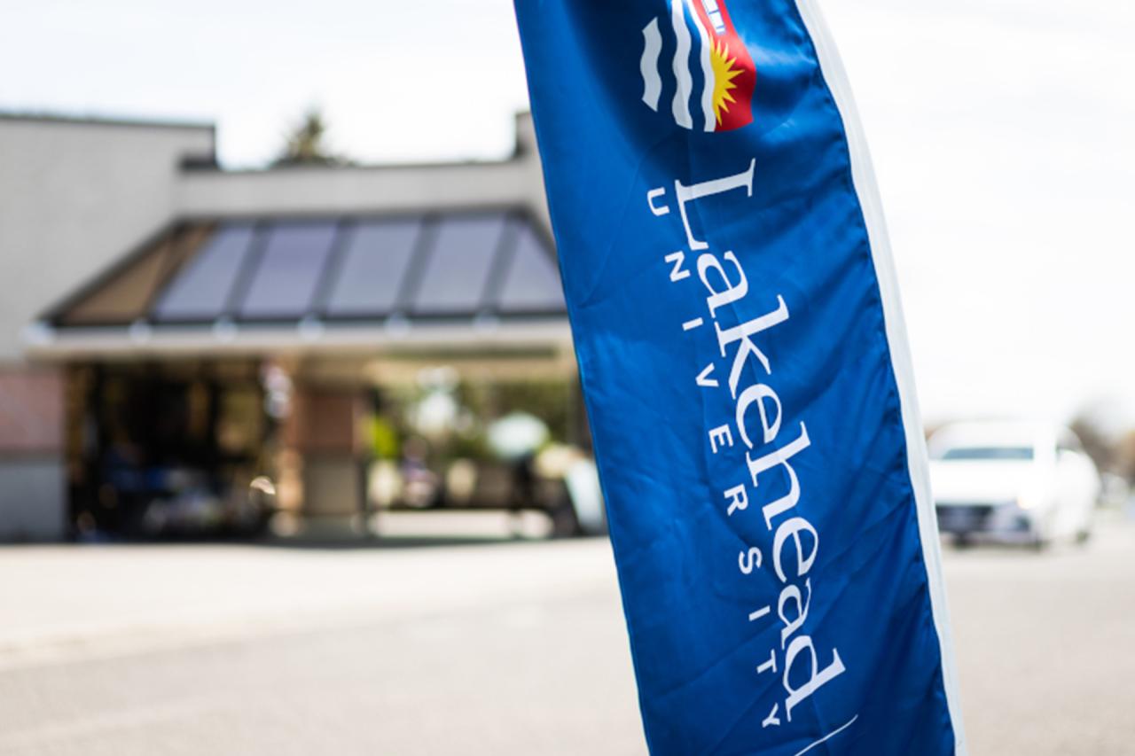 Lakehead University Flag with Lakehead building in the background, out of focus