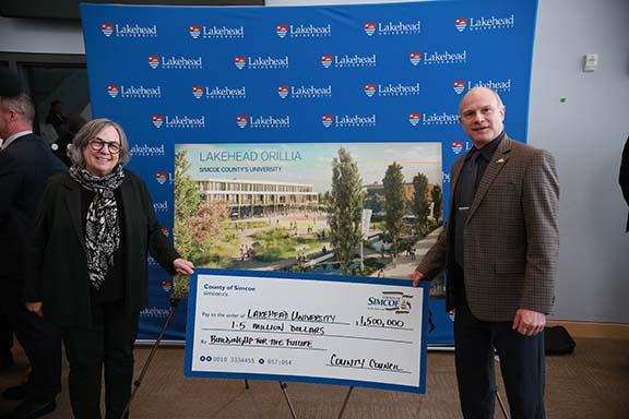 County Warden Basil Clarke presents a $1.5 million cheque to Lakehead President Dr. Gillian Siddall as the first installment of a $15 million commitment was celebrated on the Orillia Campus. 